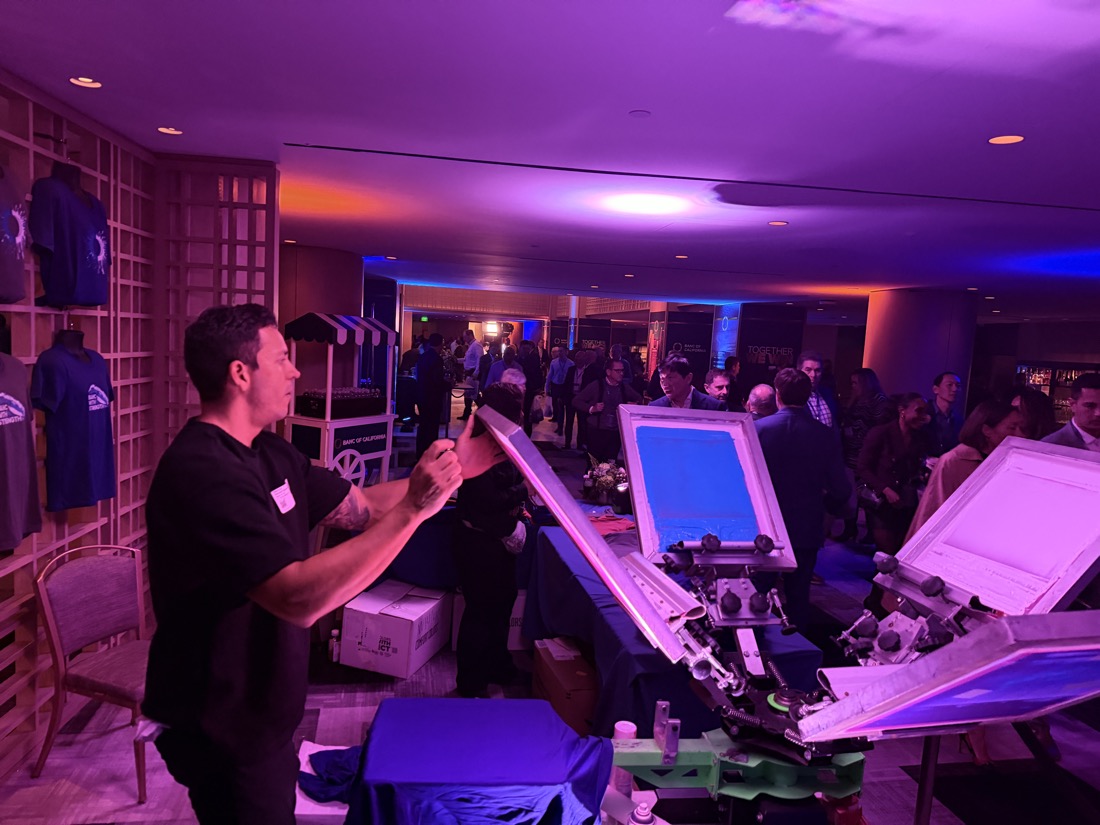 Attendant pressing pieces while the reception crowd mingles in the background