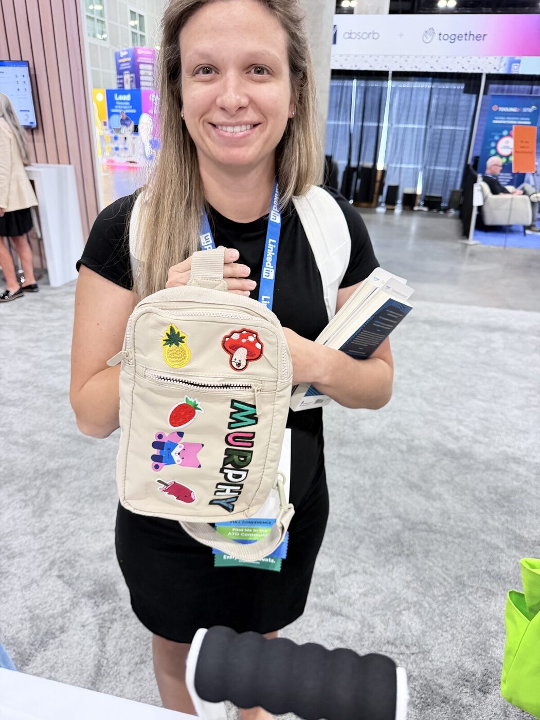 Smiling guest holding a cream canvas bag personalized with chenille letters spelling her name plus fruit and mushroom patches